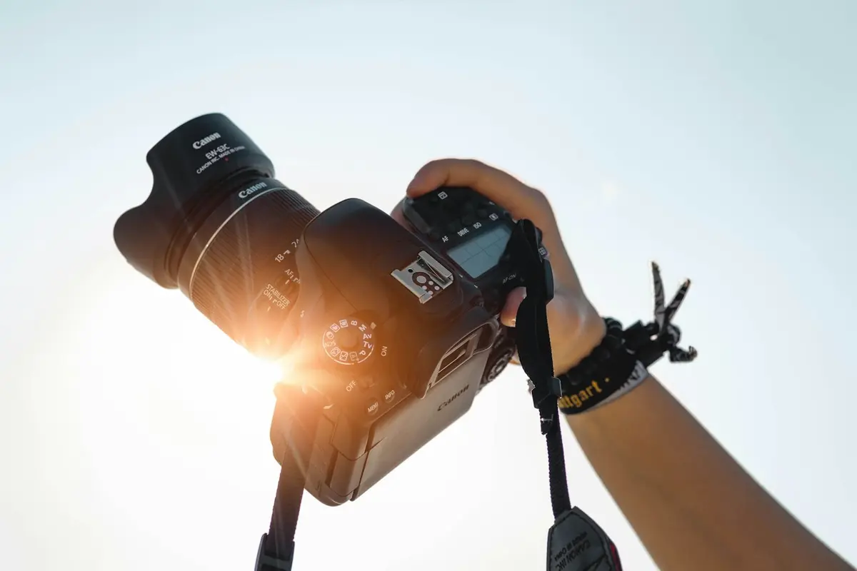 Photographer holding a camera into the sunlight