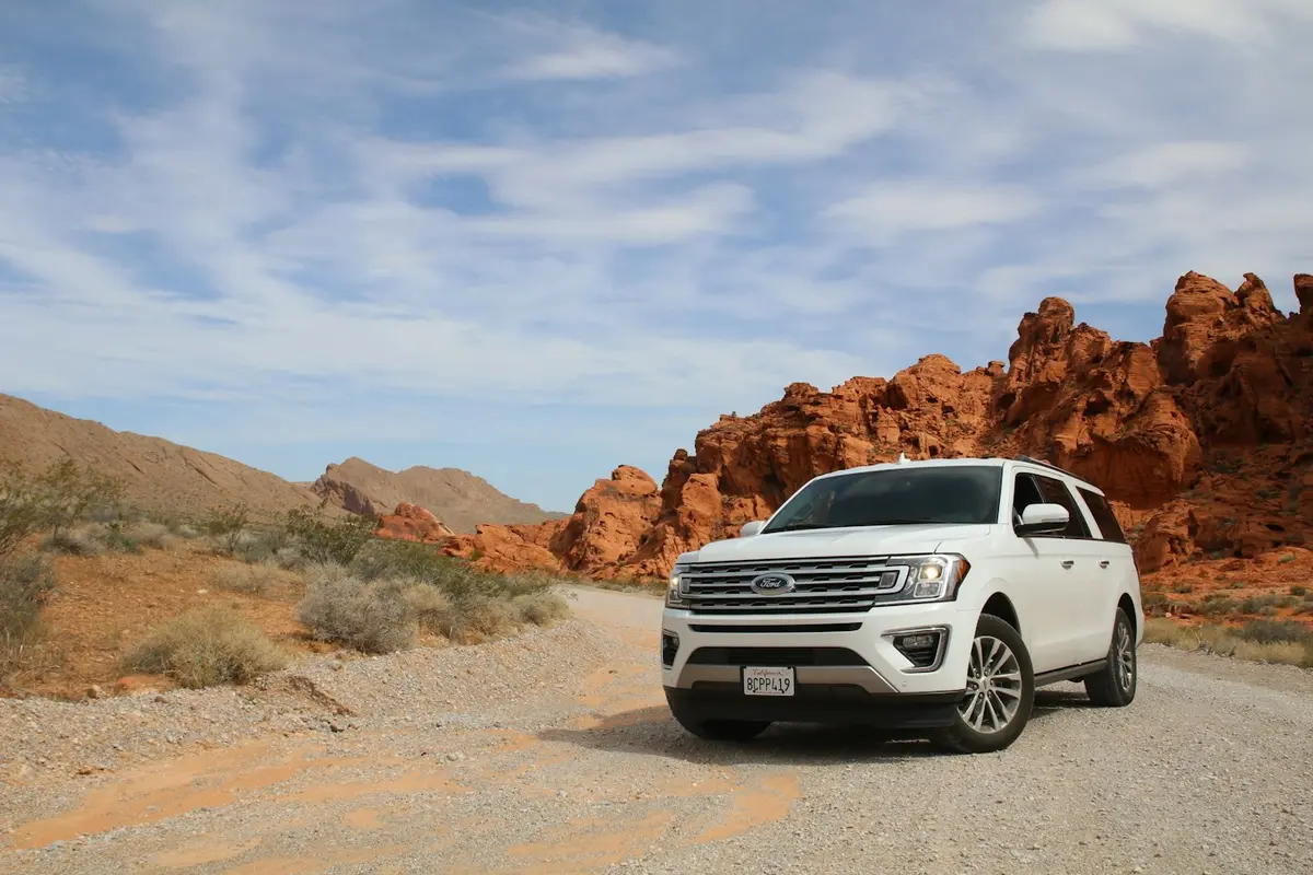 Off road vehicle on a dusty trail under red rocks