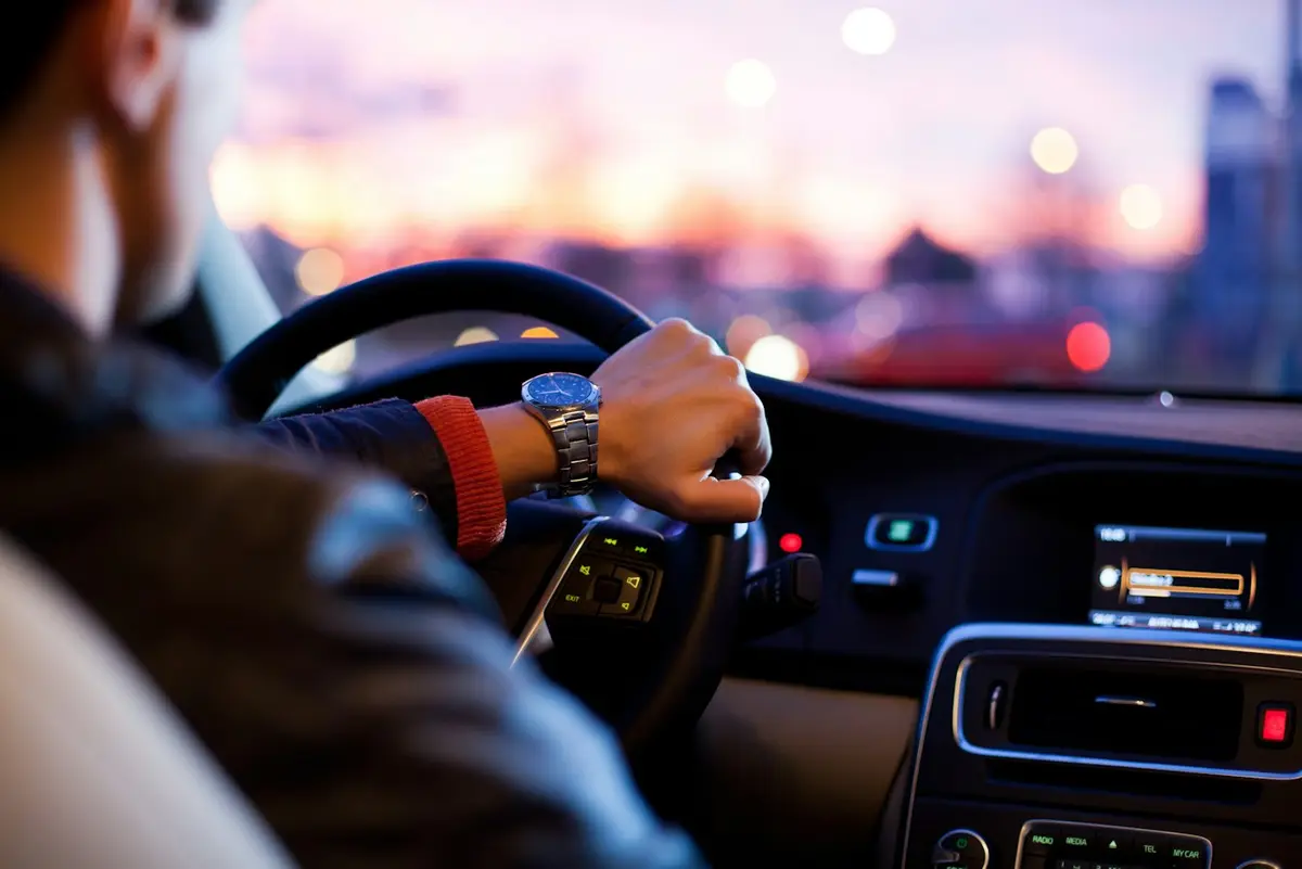 Hands on the wheel driving towards the evening light