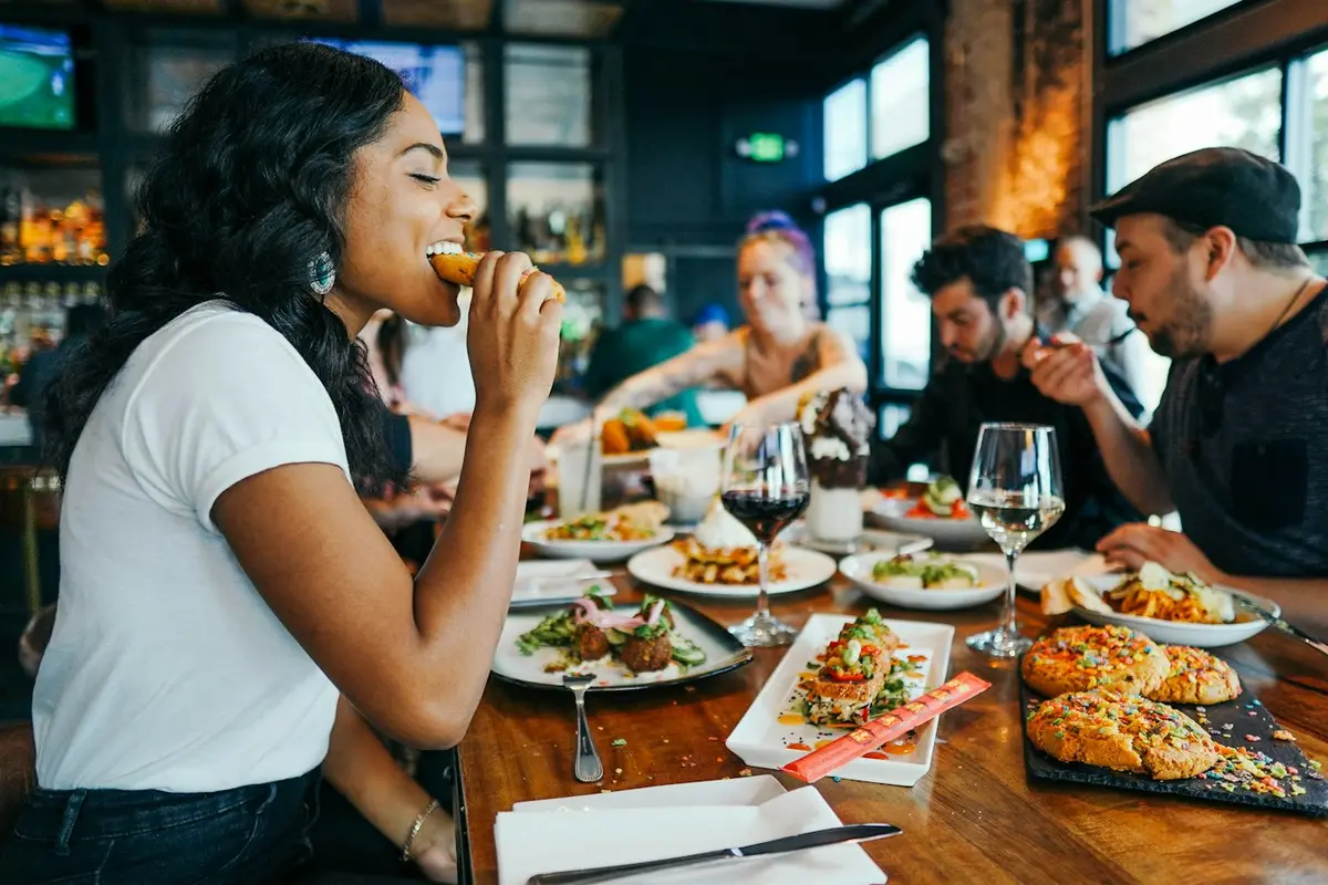 Friends laughing around a table of shared dishes