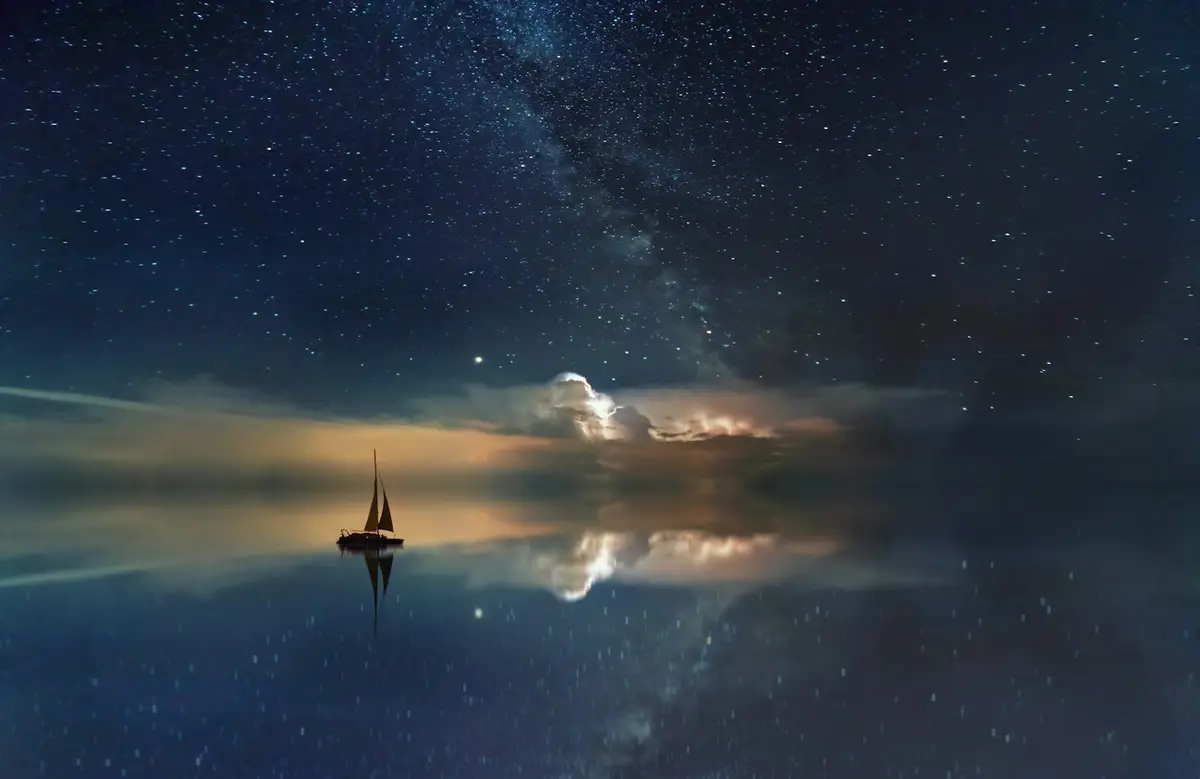 Sailboat silhouetted on still water at dusk
