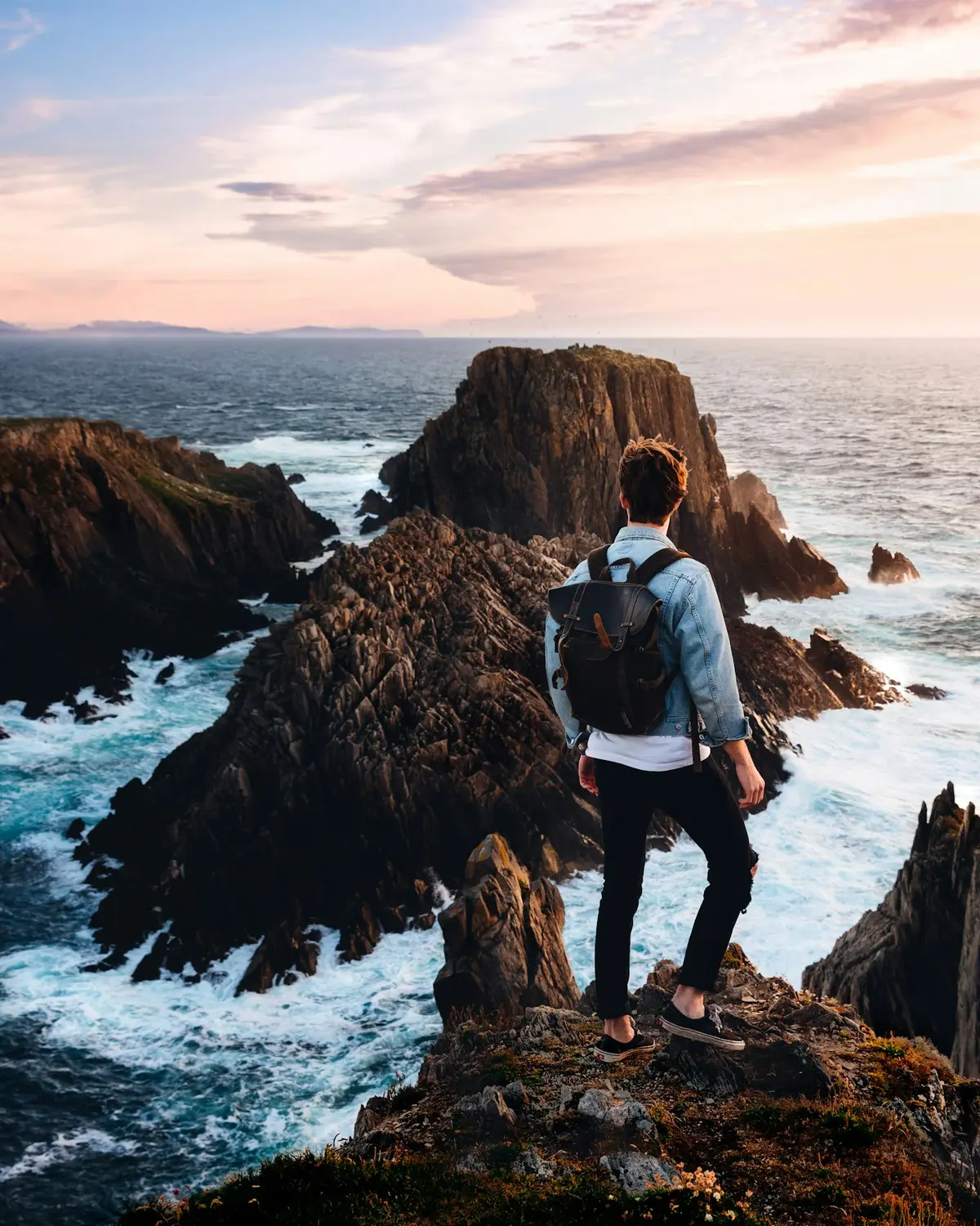 Traveller looking out over a rugged rocky coastline