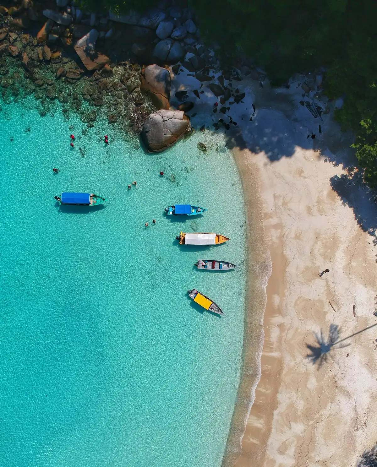 Small boats moored in shallow turquoise water off a beach